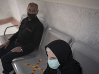 An Iranian elderly woman wearing a protective face mask sits at a corridor while waiting to receive a dose of the China's Sinopharm new coro...
