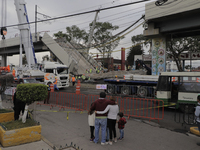 Passers-by watch emergency work and debris removal at ground zero between Tezonco and Olivos stations on Line 12 of the Metro Collective Tra...