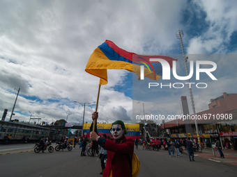 A demonstrator dressed as The Joker character waves a Colombian flag as thousands flood Bogota, Colombia on may 12, 2021 to protest against...