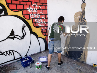 A street artist seen drawing a graffiti on a wall in Athens, Greece on May 13, 2021. The graffiti depicts a Palestinian woman holding a slin...