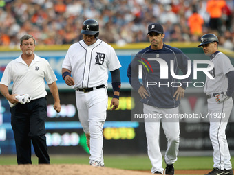 Detroit Tigers Miguel Cabrera walks off the field flanked by Manager Brad Ausmus and Trainer Kevin Rand as the first base coach Omar Vizquel...