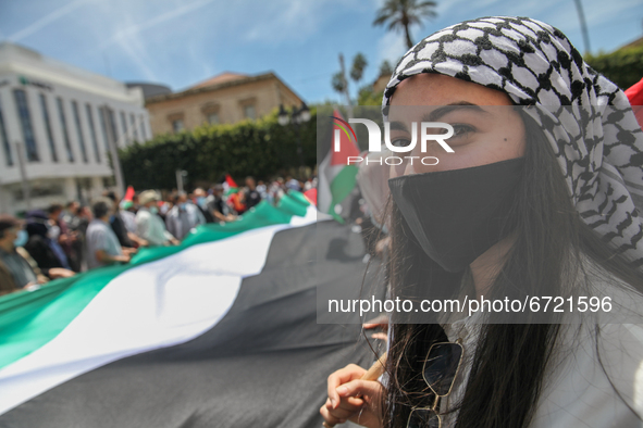 A Tunisian female protester wearing the Palestinian keffiyeh, holds a giant flag of Palestine, during a demonstration held by thousands of T...