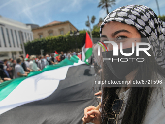 A Tunisian female protester wearing the Palestinian keffiyeh, holds a giant flag of Palestine, during a demonstration held by thousands of T...
