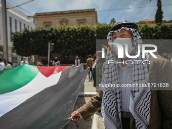 An elderly man wearing the Palestinian keffiyeh, holds a giant flag of Palestine, during a demonstration held by thousands of Tunisian an Pa...