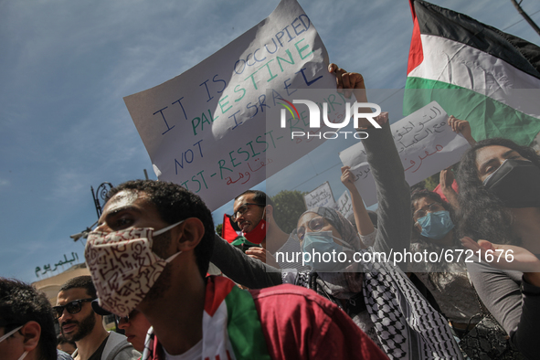 A female protester lifts a placard that reads in english, it is called Occupied Palestine not Israel, Resist, Return, as other protesters wa...