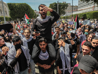 A demonstrator on top of a protester's shoulders, gestures and shouts anti-Israel slogans as other protesters wearing the Palestinian keffiy...