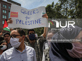 A protester lifts a placard that reads in english, Queers for Palestine as an other protester waves the Palestinian flag during a demonstrat...