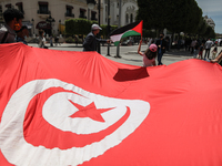 Protester wave a giant flag of Tunisia as a little girl waves the Palestinian flag during a demonstration held by thousands of Tunisian an P...