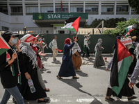 Female protesters wave the Palestinian flag as they shout anti-Israel slogans during a march held on the street in the capital Tunis, Tunisi...