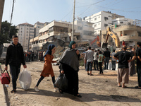 Palestinian families walk past destroyed buildings as they leave their homes in Gaza City with some belongings to shelter in a safer neighbo...