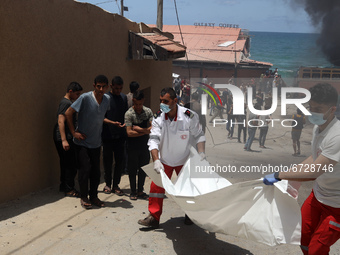 Palestinian rescue workers carry the remains of a man found next to a beachside cafe after it was hit by an Israeli airstrike, in Gaza City,...