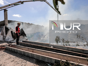Palestinian firefighters douse a huge fire at the Foamco mattrss factory east of Jabalia in the northren Gaza Strip, on May 17, 2021. (