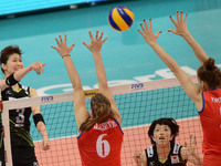 Saori Kimura (L) of Japan spikes the ball as Serbia player attemp to block during their FIVB World Grand Prix intercontinental round match a...