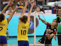 Malika Kanthong (#15) of Thailand spikes the ball as Brazil players attemp to block during their FIVB World Grand Prix intercontinental roun...