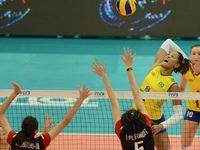 Adenizia Silva (Top) of Brazil spikes the ball as Thailand players attemp to block during their FIVB World Grand Prix intercontinental round...