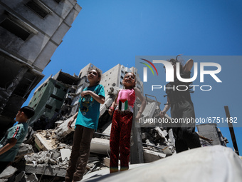 Palestinian children play on May 24, 2021 next to buildings heavily damaged by Israeli air strikes earlier this month in  Gaza City. - A cea...