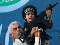 Yahya Sinwar, Palestinian leader of Hamas in the Gaza Strip, second left, holds a child in a soldier costume, on stage with a weapon for the...
