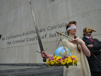 Extinction Rebellion activists, Ceara Carney dresses blindfolded in a gown as Lady Justice and Louis Heath wearing a suit to represent the s...
