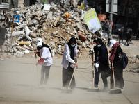 Palestinian volunteers sweep the rubble of buildings, recently destroyed by Israeli strikes, in Gaza City's Rimal district on May 25, 2021....