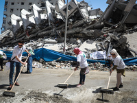 Palestinian volunteers sweep the rubble of buildings, recently destroyed by Israeli strikes, in Gaza City's Rimal district on May 25, 2021....