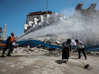 Palestinian volunteers and municipal workers clear the rubble of buildings, recently destroyed by Israeli strikes, in Gaza City's Rimal dist...