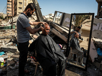 A Palestinian barber works next to the ruins of buildings and shops destroyed by Israeli strikes, in Gaza City, on May 25, 2021. - A ceasefi...