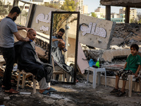 A Palestinian barber works next to the ruins of buildings and shops destroyed by Israeli strikes, in Gaza City, on May 25, 2021. - A ceasefi...