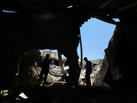Palestinian workers salvage items from a damaged factory in Gaza's industrial area, on May 25, 2021, which was hit by Israeli strikes prior...