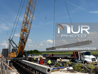 A crane lifts a pile for a bridge over the St. Johns River during the construction of the $2.7 billion, 170-mile Brightline high-speed rail...