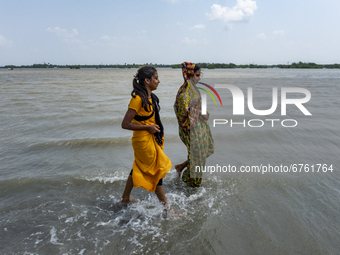 Two village girls are crossing the road that is full of water as river embankments have broken and several villages flooded. On May 28, 2021...