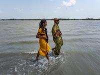 Two village girls are crossing the road that is full of water as river embankments have broken and several villages flooded. On May 28, 2021...