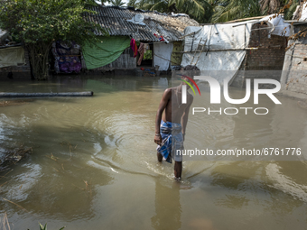 A boy is coming out of his home which is submerged in floodwater as river embankments have broken and several villages flooded. On May 28, 2...