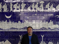 Chinese artist Ai Weiwei poses in front of one of his artworks that is made with Portuguese traditional 'azulejo' tiles during a press previ...
