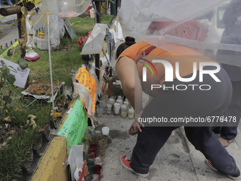 A person leaves a candle in an offering in front of the emergency zone on Avenida Tláhuac in Mexico City, after the collapse of a column on...