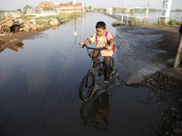 Students going to school crossing unindated road due to the tidal floods in Pekalongan city, Central Java province, on June 5, 2021. Base on...