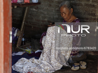 Mrs Waryuni (70), continue to work on her batik cloth manually at her home after the tidal flood receded in jeruk sari village, Pekalongan c...