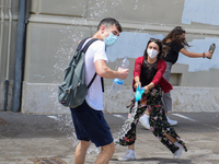 Last day of lessons of a difficult school year, smiles hidden among the masks and water balloons to celebrate the last day of school, with t...