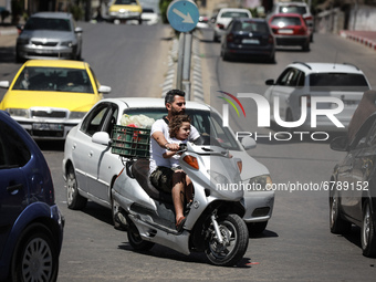 A Palestinian father and his daughter ride a motorcycle in the streets in Gaza City, on June 8, 2021. 
 (