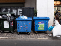 A woman is throwing recycling bags in the recycling bin near Monastiraki square in Athens, Greece on June 9, 2021. (