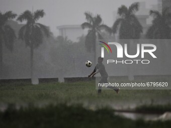 A boy plays football during rain at a park area in Dhaka, Bangladesh on June 11, 2021. (