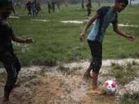 Boys play football during rain at a park area in Dhaka, Bangladesh on June 11, 2021. (