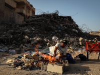 A Palestinian man burns documents past the rubble of a building destroyed during the May 2021 conflict between Hamas and Israel in Gaza City...