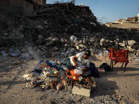 A Palestinian man burns documents past the rubble of a building destroyed during the May 2021 conflict between Hamas and Israel in Gaza City...