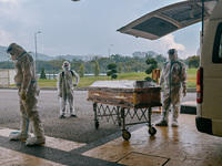 Crematorium workers wearing protective suit wait for official clearance before pushing the casket of Covid-19 coronavirus patient for cremat...