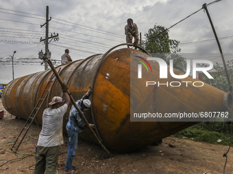 Labourer works on the construction of a cement silo in a factory at Savar, on the outskirts of Dhaka on June 16, 2021. (