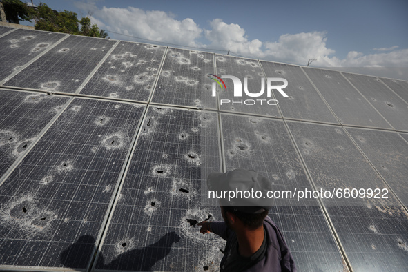 A Palestinian farmer inspects damage at his solar energy, which was destroyed by Israeli air strikes during the May 2021 conflict between Ha...