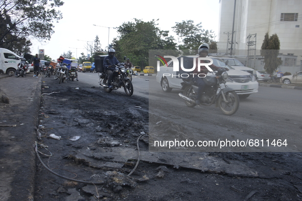 Motorcyclists ride through debris at the scene of a gasoline explosion on Mobolaji Bank Anthony way district of Lagos, on June 18, 2021. A t...