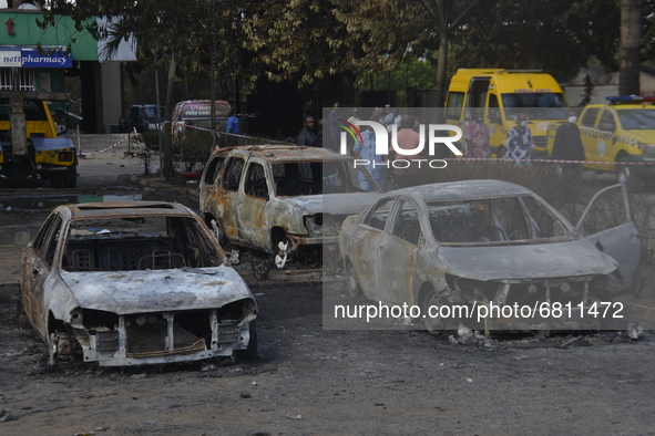 People stand next to wreckage of burnt cars after a gasoline tanker explosion on Mobolaji Bank Anthony way district of Lagos, on June 18, 20...
