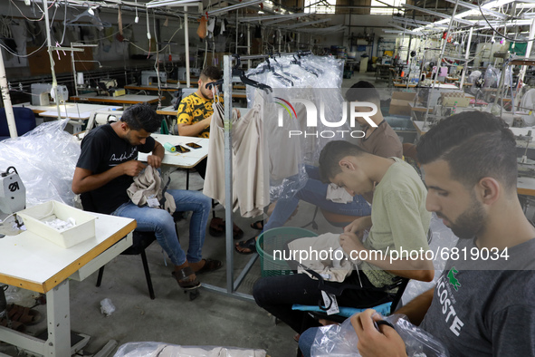 Palestinian tailors work at an empty clothing factory in Gaza's industrial zone on June 21, 2021. - Israel lifted some restrictions it had i...
