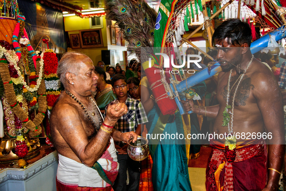 Tamil Hindu priest splashes water on the face of a Hindu devotee before blessing him after the devotee completed the Kavadi Attam ritual (a...